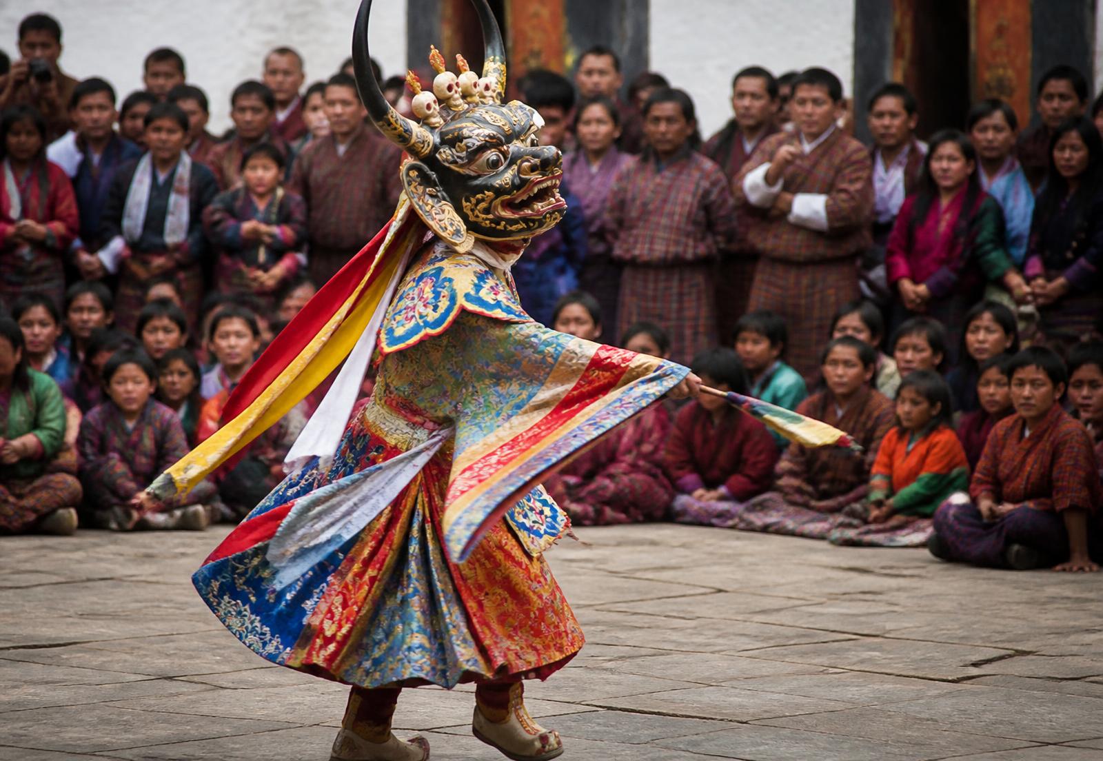 Masked Bhutanese cham dancer performing in a monastery courtyard