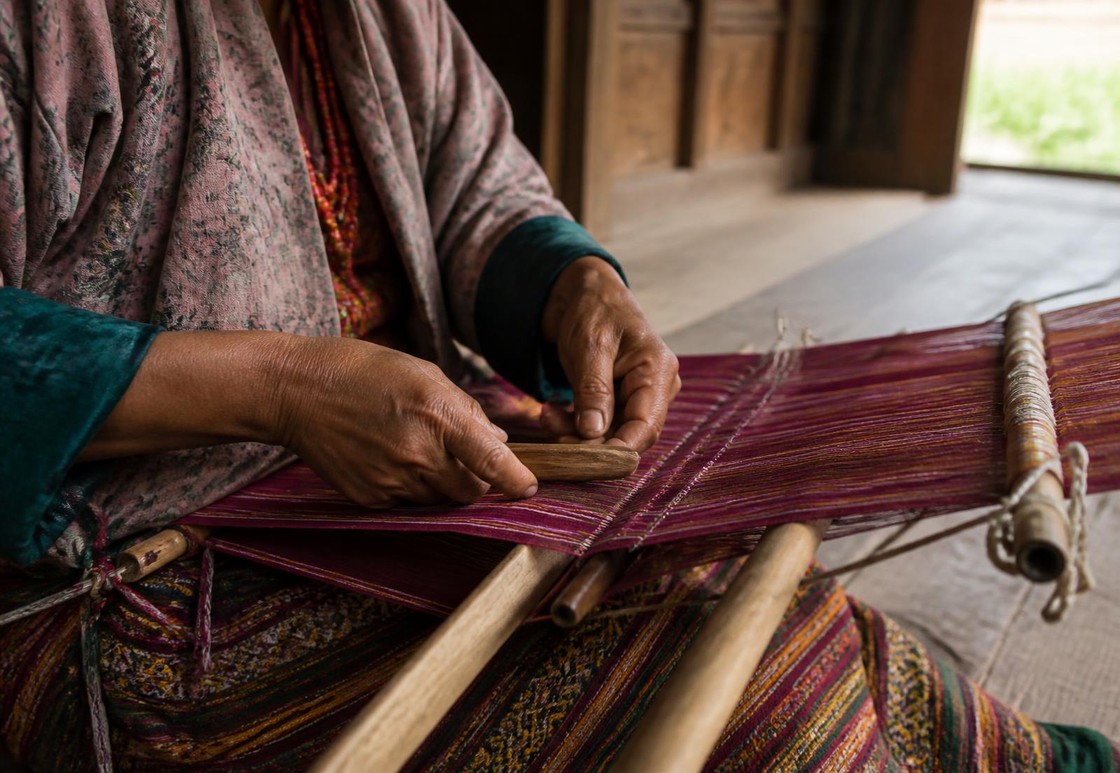 Bhutanese weaver working at a traditional wooden loom